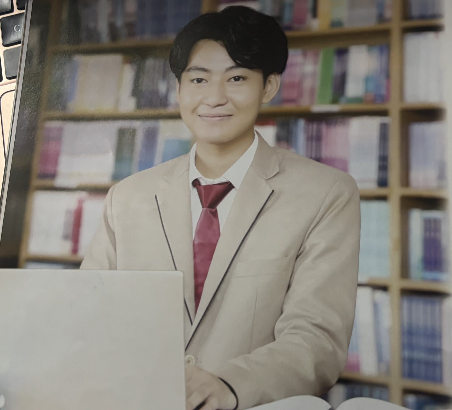 A BCA student smiling in front of a library bookshelf