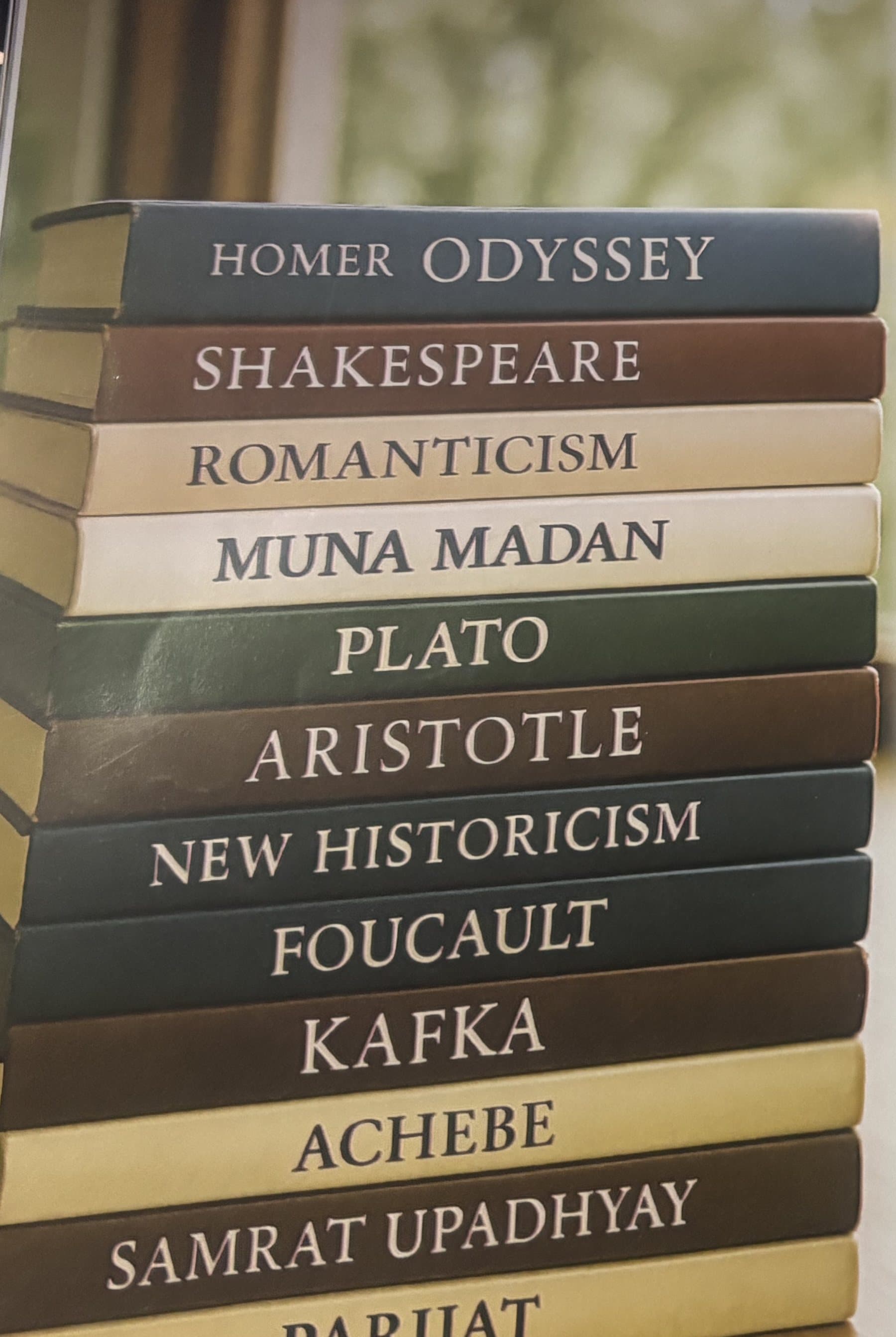 A stack of literature books spanning Homer to Samrat Upadhyay
