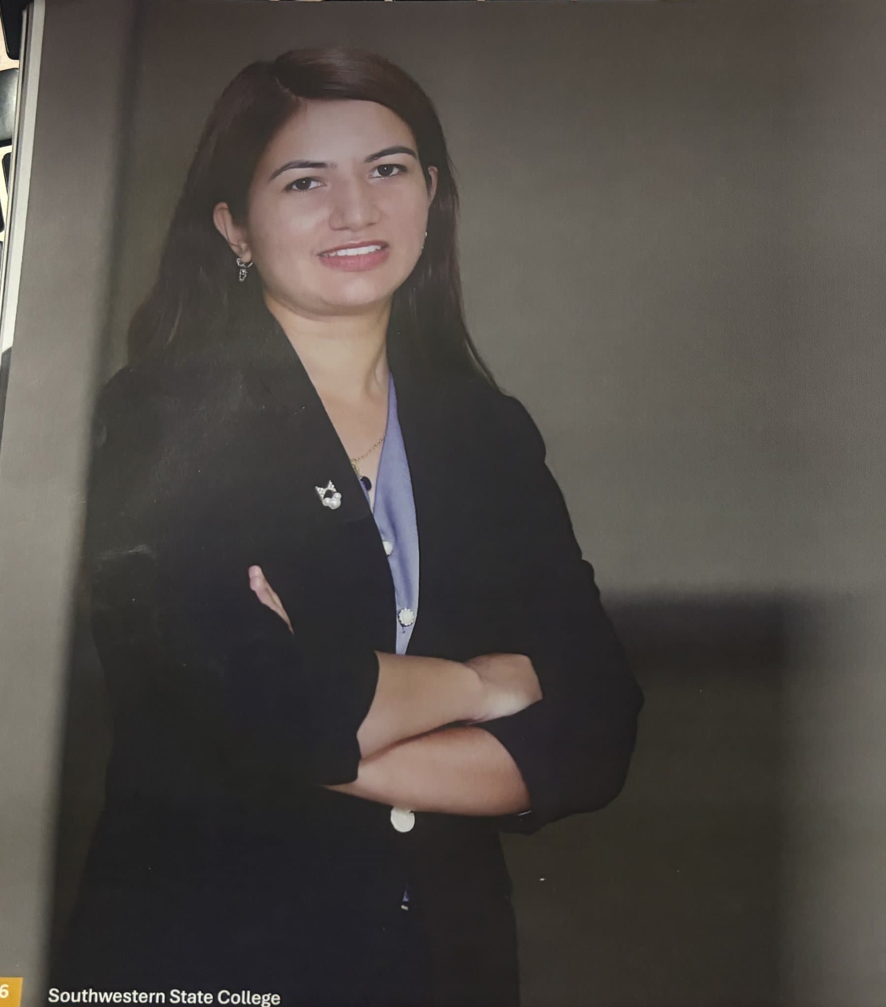 An MBS student with arms crossed in a dark blazer